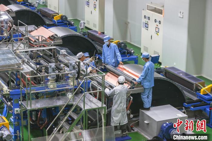 图为广东嘉元科技股份有限公司龙南项目的生产车间，几位工作人员正在调试设备。(资料图) 刘力鑫 摄